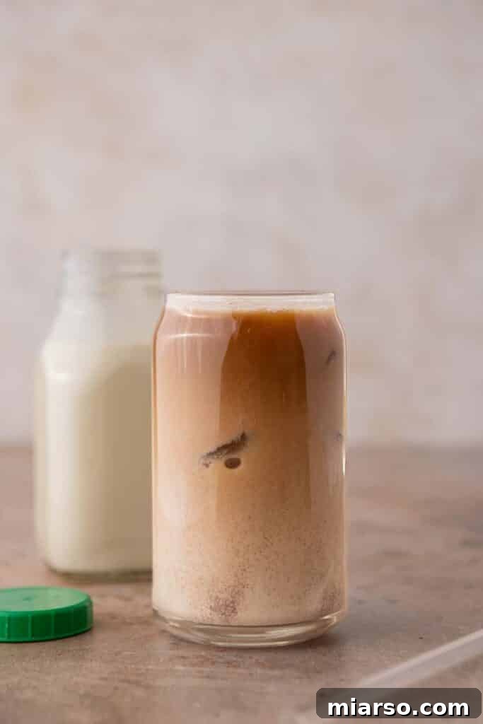 A glass of cold brew coffee with a splash of homemade Italian sweet cream being poured in, creating a beautiful swirl.