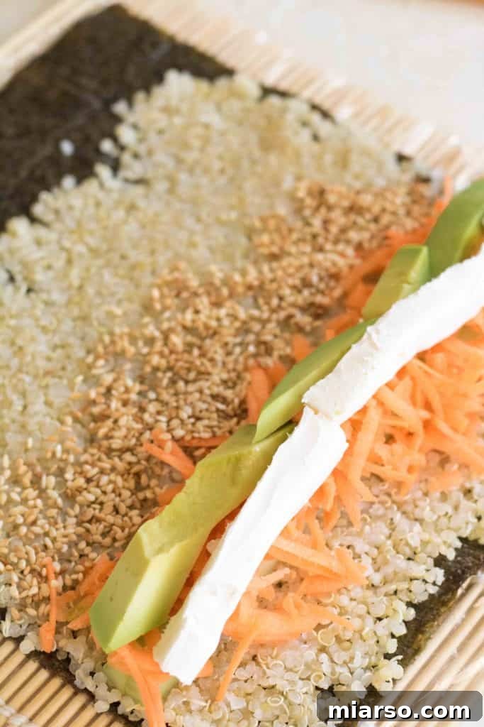 Adding cream cheese and sesame seeds to the quinoa sushi roll.