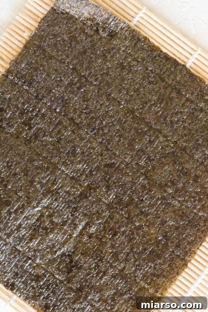Sushi rolling mat covered with plastic wrap, ready for assembly.