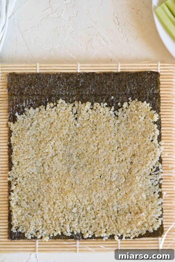 Spreading quinoa evenly on a nori sheet, leaving a border.