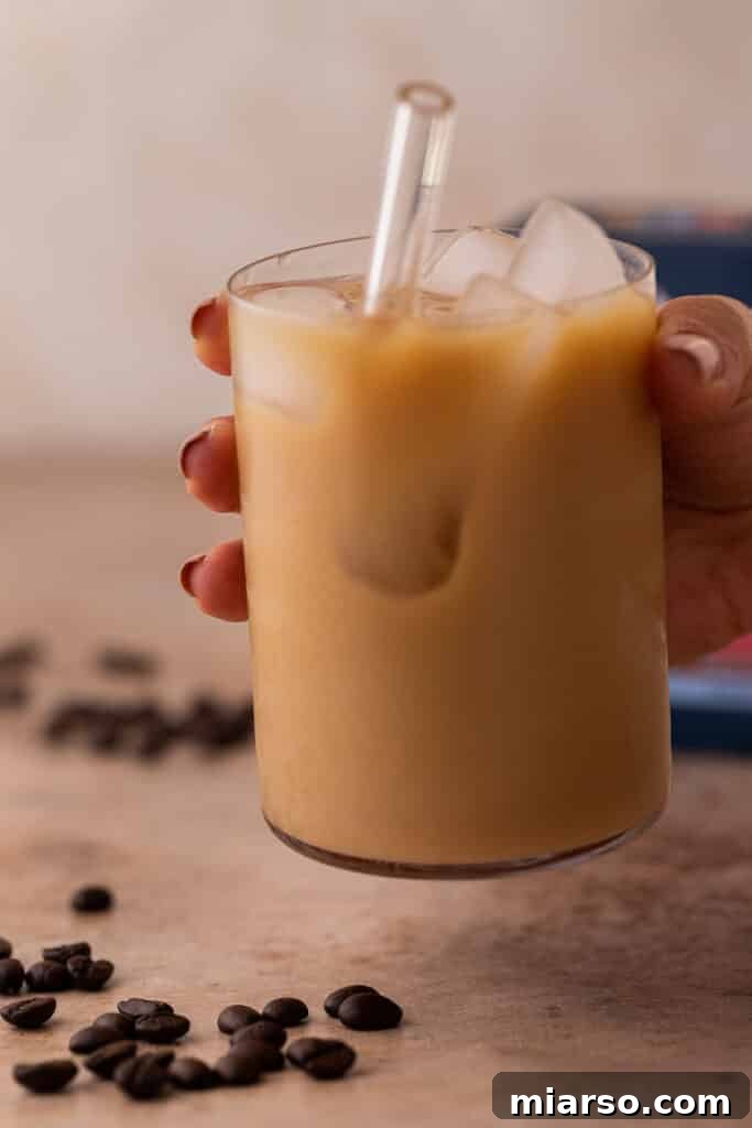 Emma Chamberlain Cold Brew in a glass with creamer being poured in, illustrating customization options.