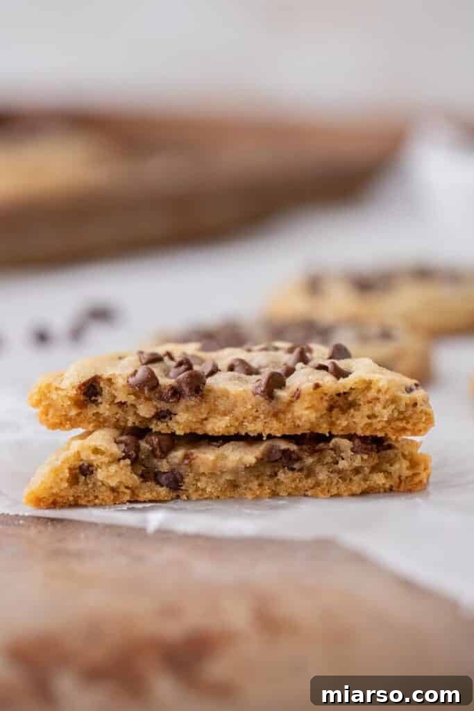 Inside texture of a soft chocolate chip sugar cookie split in half, revealing its chewy center and melted chocolate chips.