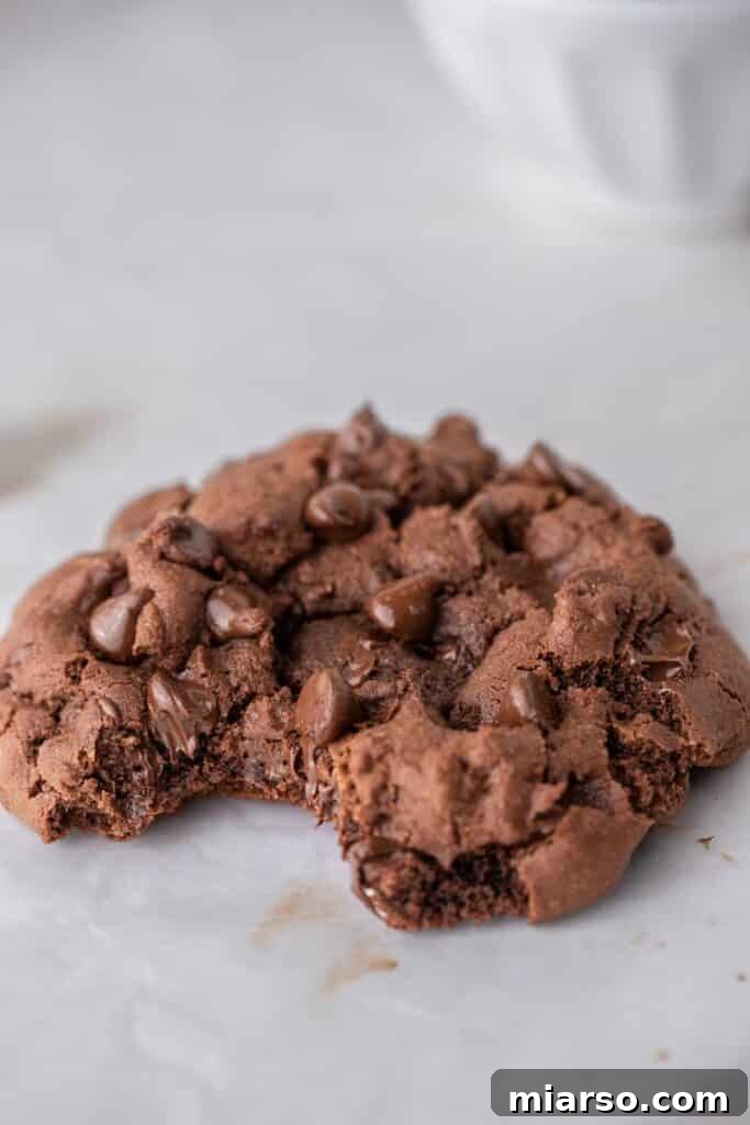A single serve double chocolate cookie with a bite taken out, revealing its soft, gooey interior and melted chocolate chips.
