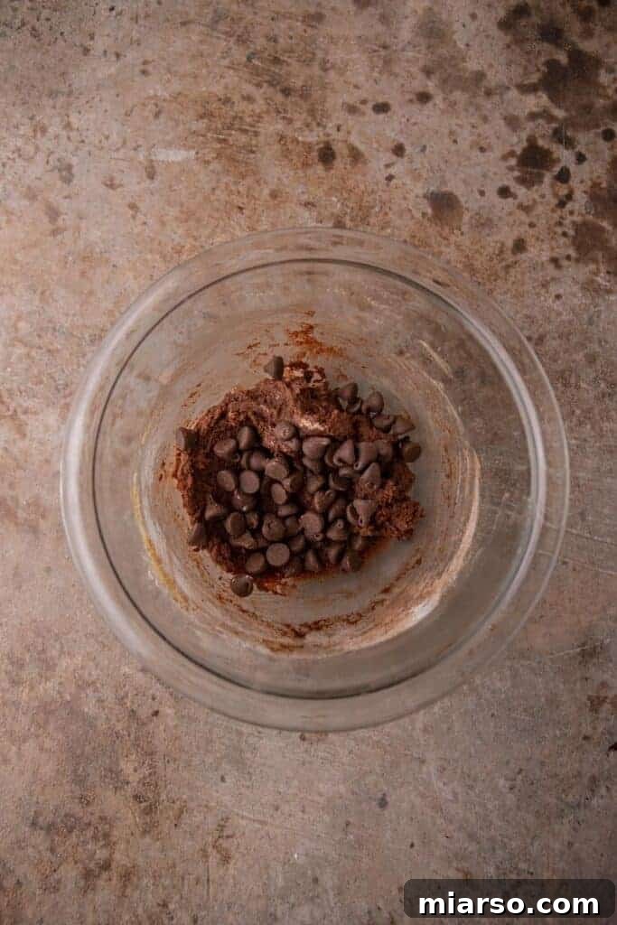 Freshly mixed double chocolate cookie dough in a bowl, speckled with chocolate chips, ready for baking.