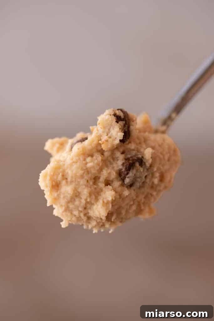 A spoon taking a scoop of cottage cheese cookie dough from a bowl.