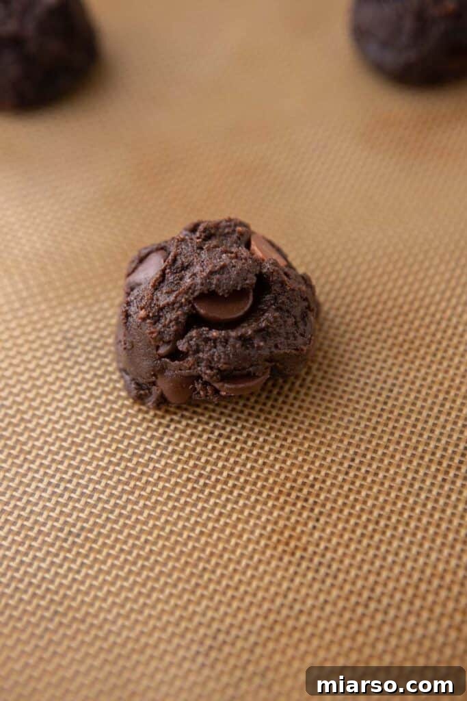 Your New Favorite Brownie Mix Cookies 7 Scooped brownie mix cookie dough balls arranged on a parchment-lined baking sheet, spaced for baking.
