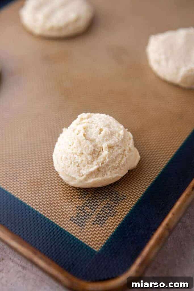 Scooped cookie dough balls arranged on a baking sheet, ready for the oven.