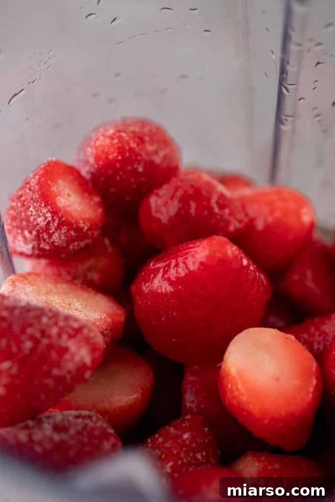Tequila and ice cubes added to the blender with strawberries, lime, and agave.