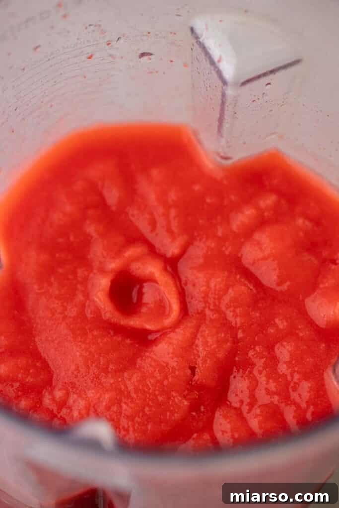 Blended frozen strawberry margarita in a blender, showing a smooth, frothy consistency.