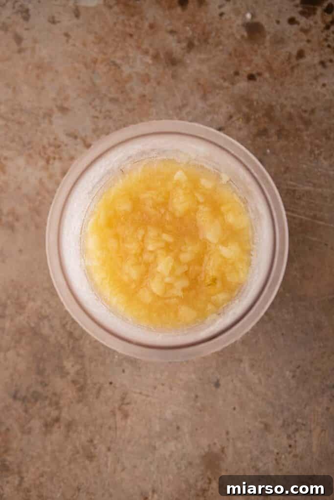 Ninja Creami cup filled with crushed pineapple mixture, ready for freezing.