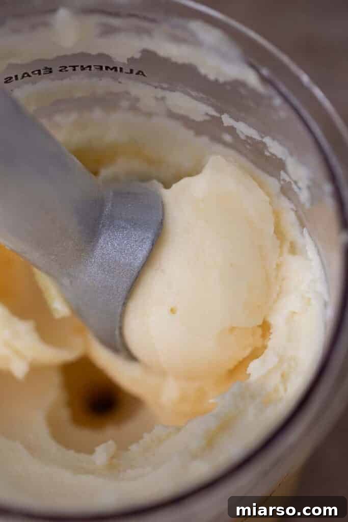 Scooping creamy Ninja Creami pineapple sorbet into a serving bowl.