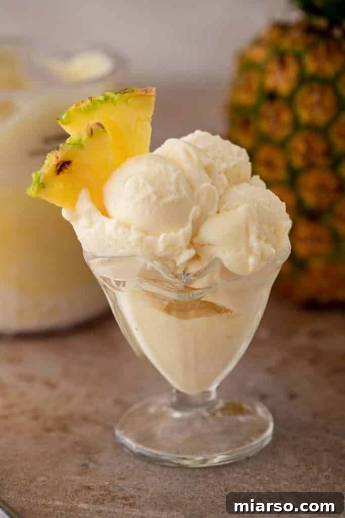 A glass of creamy Ninja Creami pineapple sorbet, garnished with a pineapple wedge.