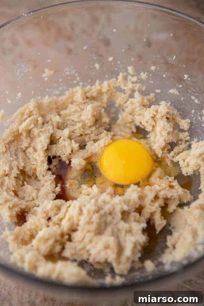 Creamed butter and sugar being mixed in a bowl with an electric mixer.