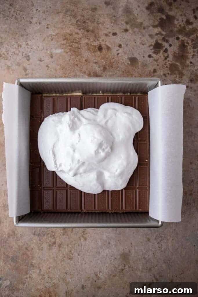 Layers of chocolate bars placed on top of cookie dough in a baking pan.