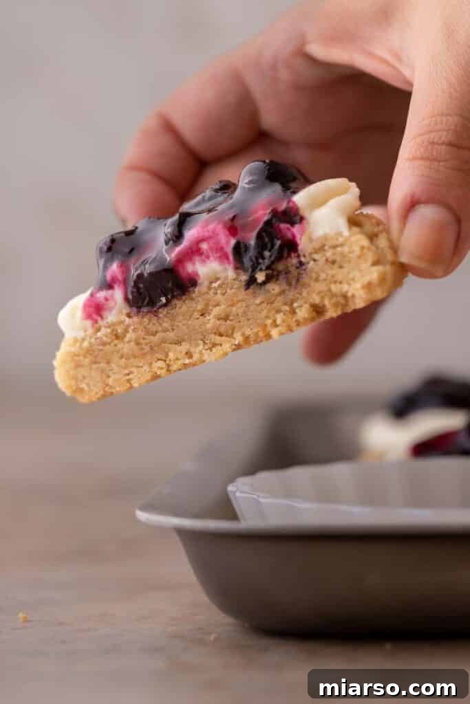 Hand holding a Crumbl blueberry cheesecake cookie