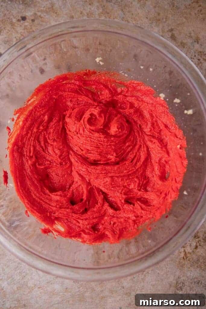 Creamed butter and sugar with red food coloring being mixed in, showing a vibrant red hue.