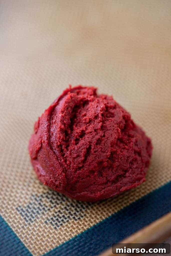 A ball of Crumbl red velvet cupcake cookie dough, perfectly rounded and ready for baking.