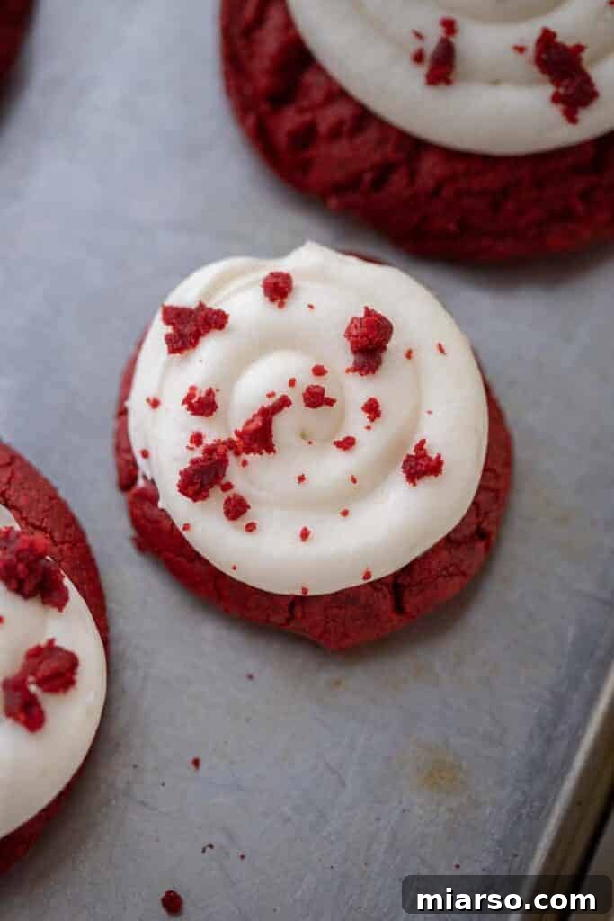 A fresh batch of baked Crumbl red velvet cupcake cookies, cooling on a baking sheet.