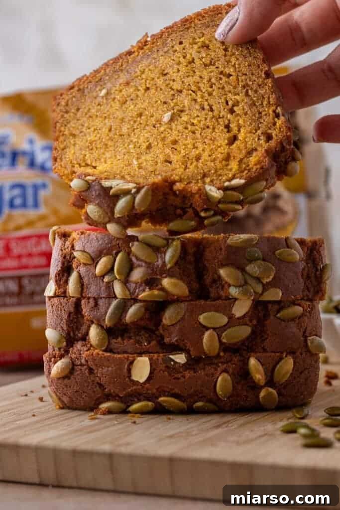 A hand holding a slice of Starbucks pumpkin bread, ready to be enjoyed.