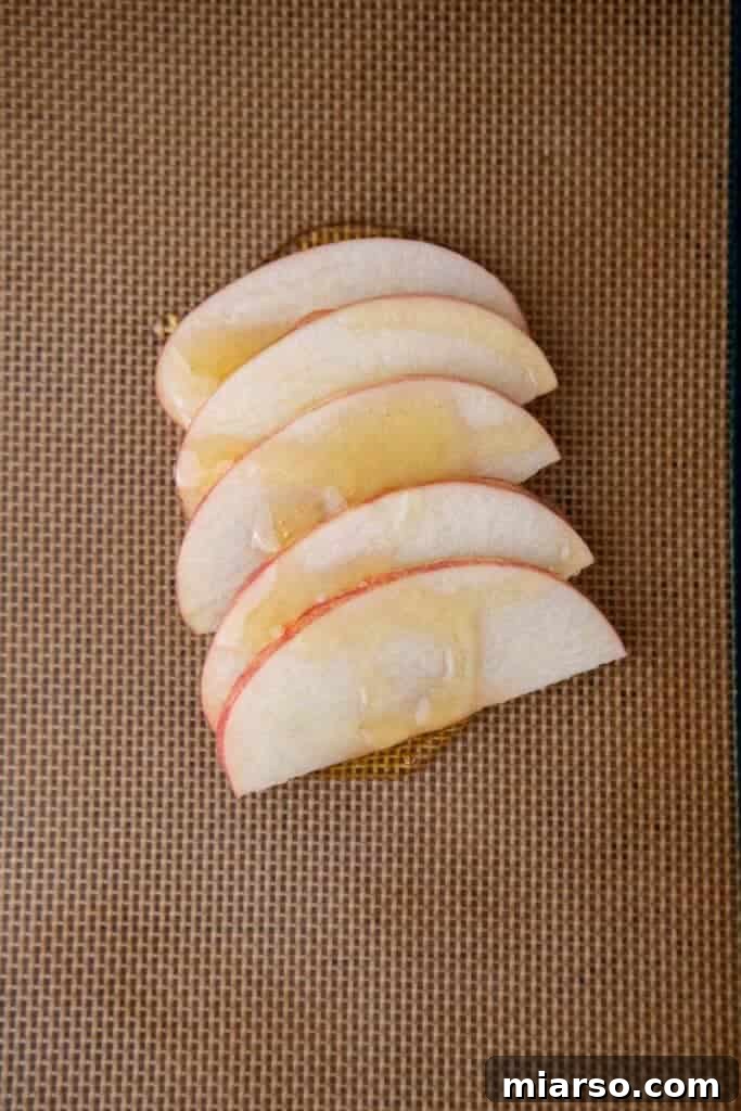 Apple slices and honey combined on a baking sheet