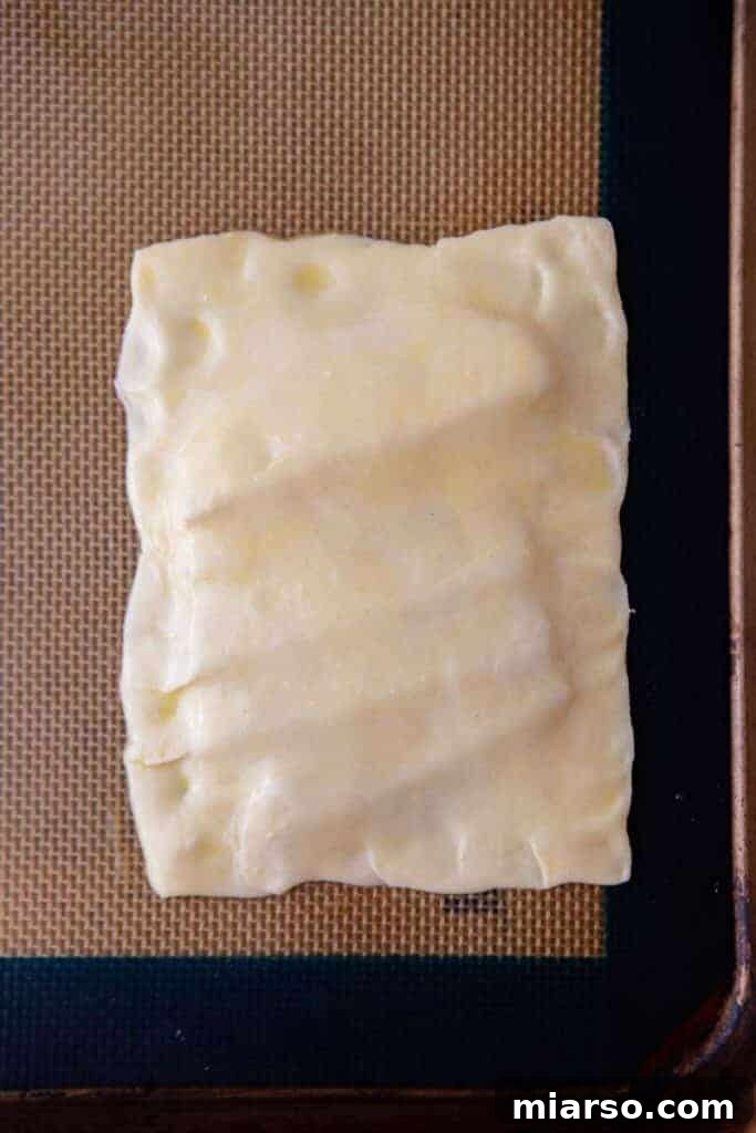 Puff pastry covering apple and honey mixture, forming mini tarte tatin