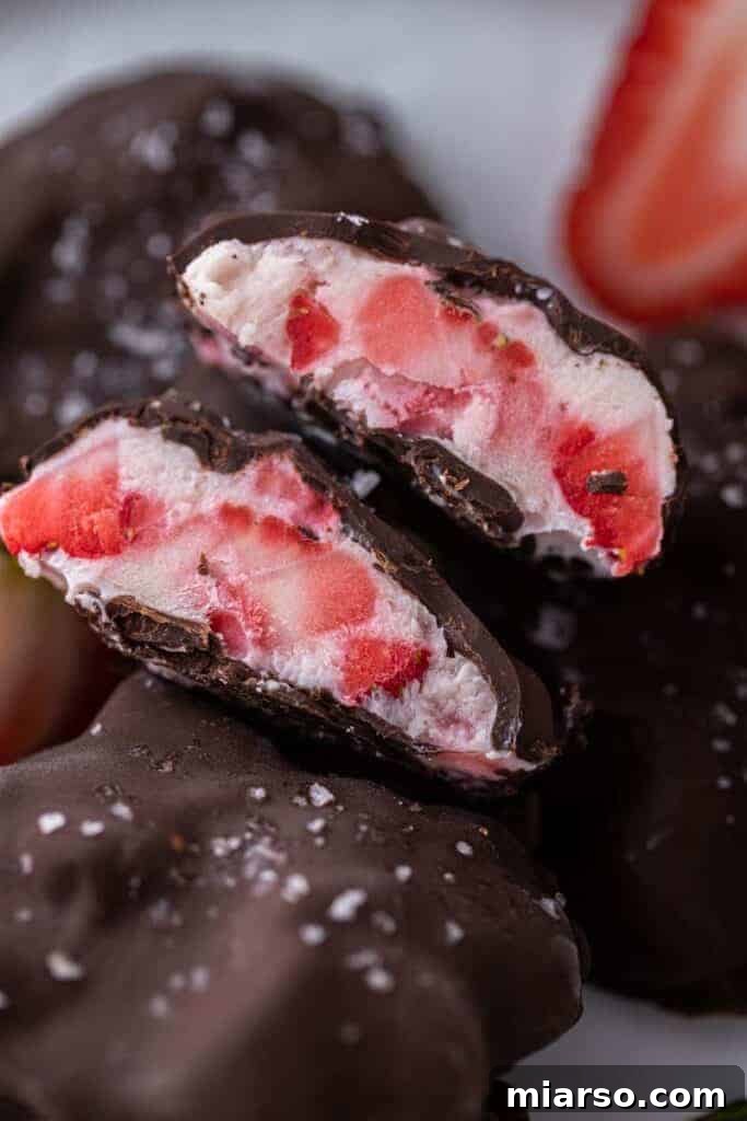 Viral Chocolate Strawberry Yogurt Clusters sliced in half, showing creamy interior and chocolate shell.