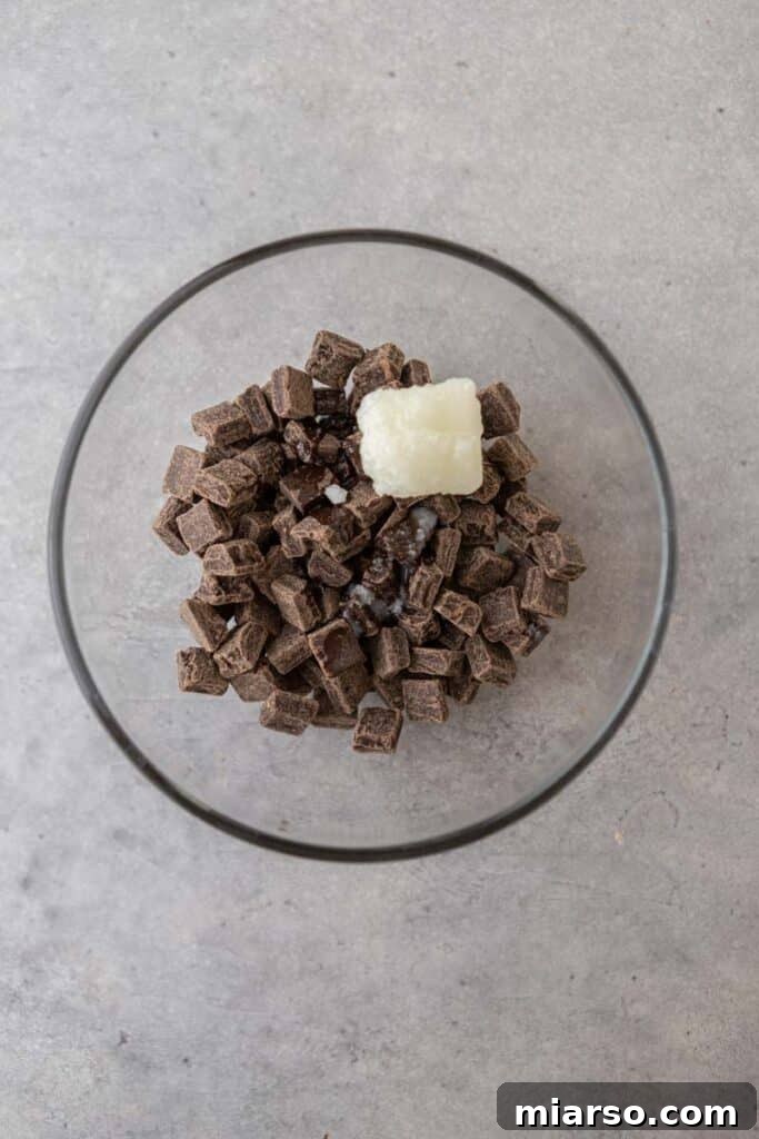 Dark chocolate chunks and coconut oil in a microwave-safe bowl, prepared for melting.