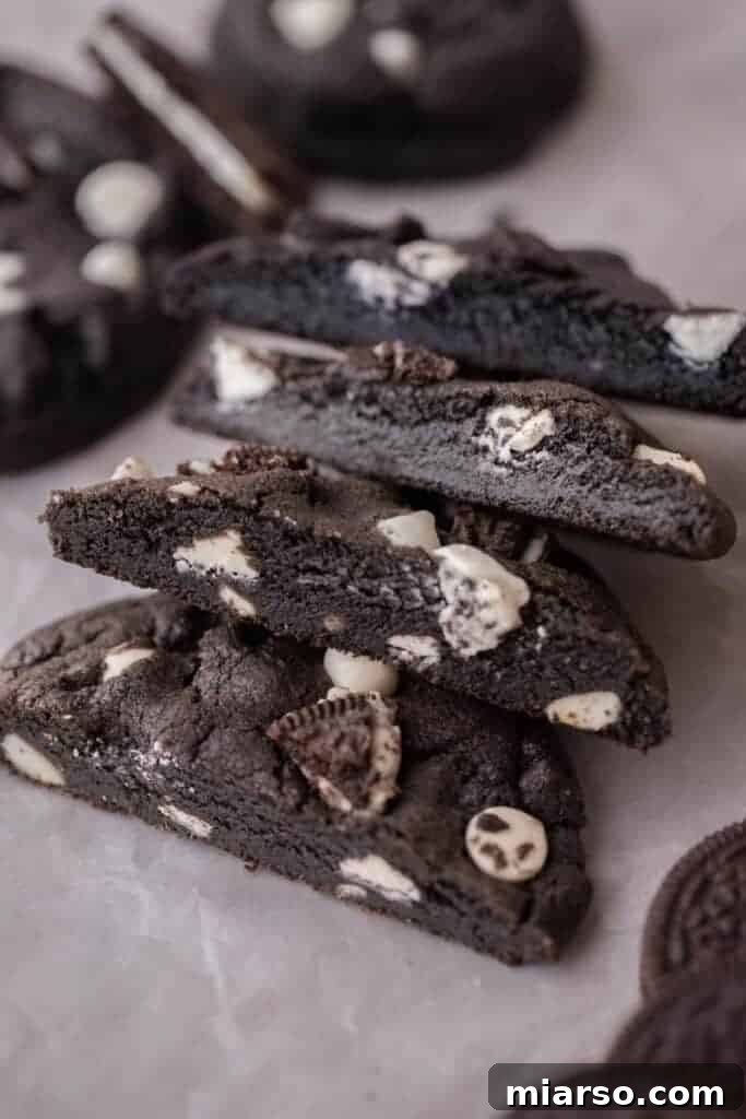 Crumbl's Chocolate Cookies & Cream Bliss 4 A stack of warm, freshly baked Crumbl Chocolate Cookies and Cream Cookies, topped with extra white chocolate chips and Oreo pieces.