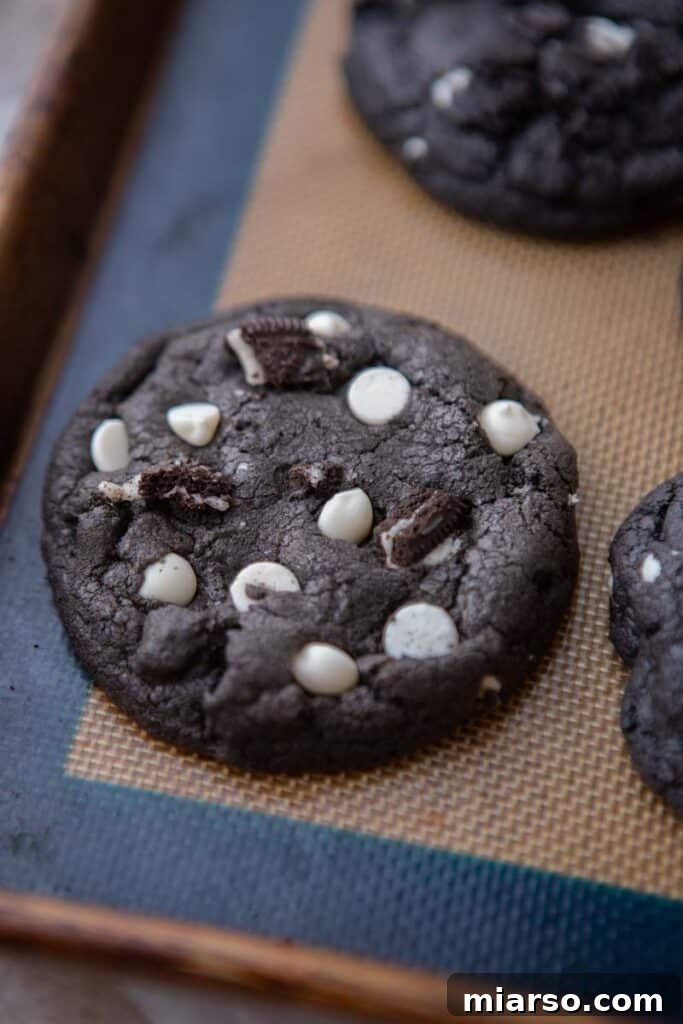 Crumbl's Chocolate Cookies & Cream Bliss 9 Freshly baked Crumbl Chocolate Cookies and Cream Cookies cooling on a baking sheet, with toppings.
