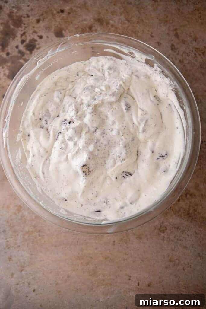 Simply Delicious No Churn Oreo Ice Cream 7 A close-up of the completed no-churn Oreo ice cream mixture in a bowl, showing the rich texture and abundant cookie pieces before freezing.