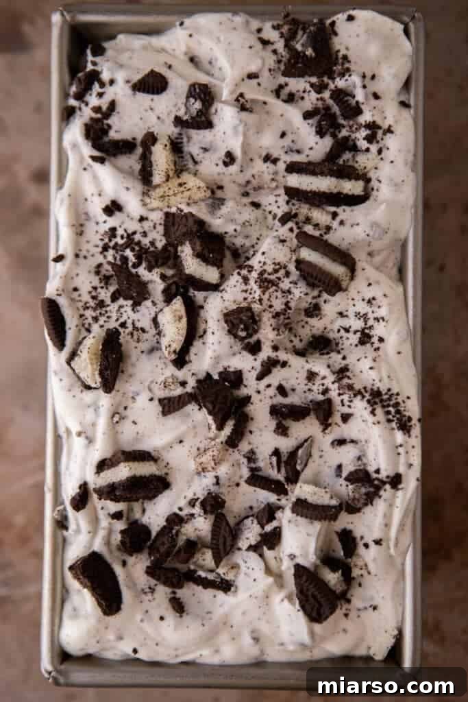 Simply Delicious No Churn Oreo Ice Cream 8 No churn cookies and cream ice cream, freshly prepared and scooped into a loaf pan, garnished with extra Oreo pieces before freezing.