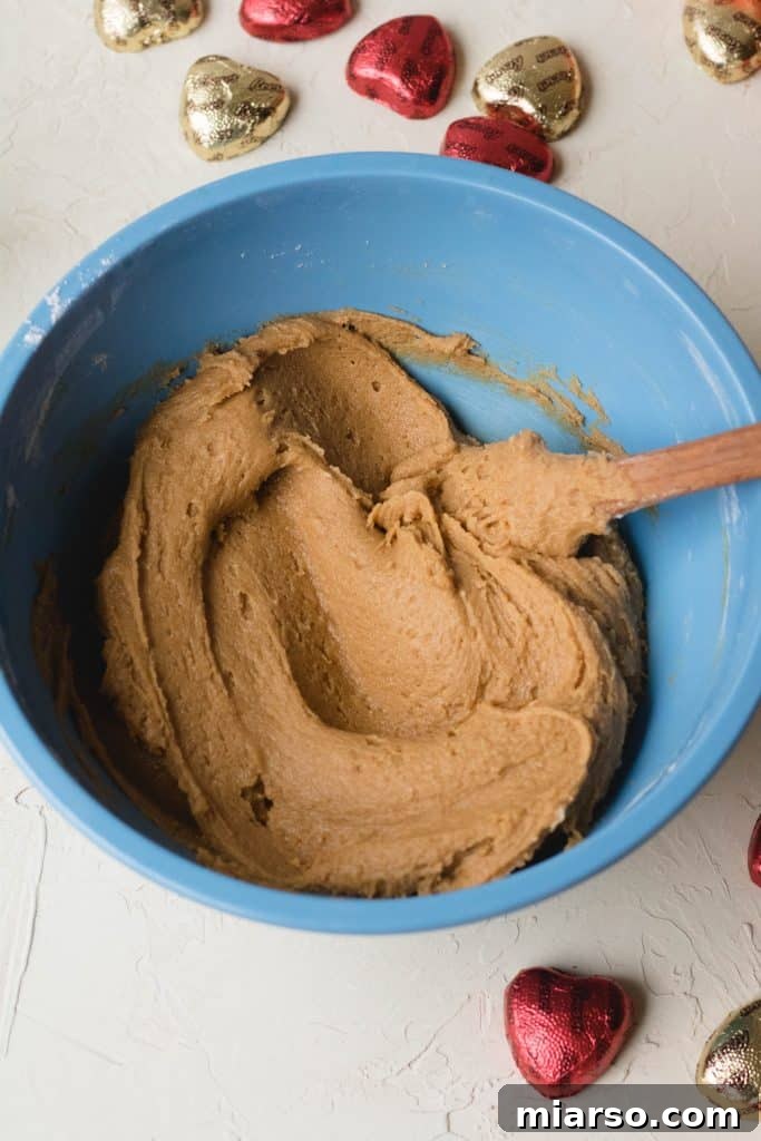 Folding dry ingredients into the blondie batter, showing thick consistency.
