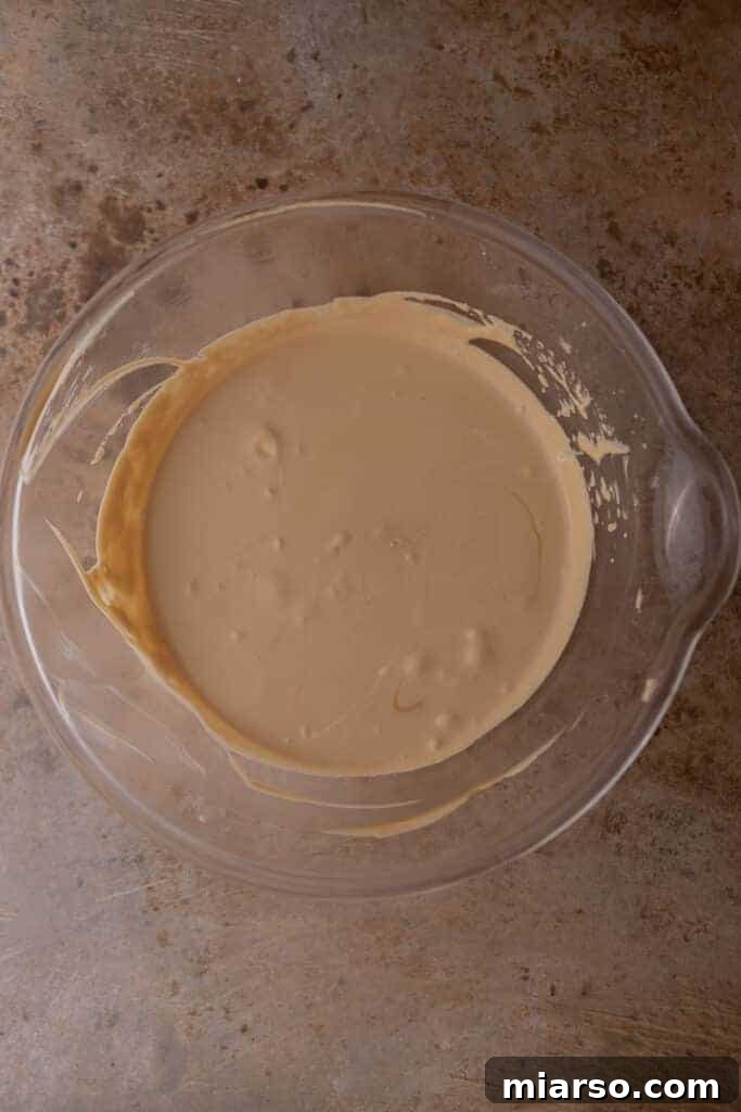 Sweetened condensed milk being folded into whipped cream, forming the rich base of the ice cream.
