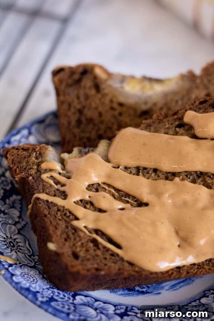 Healthy no sugar added banana bread slices on a board, with a thick layer of peanut butter and banana slices
