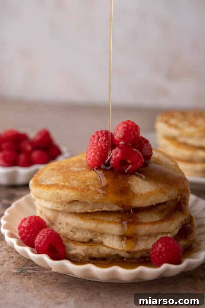 Fluffy Pancakes: No Milk, No Fuss 2 Maple syrup being drizzled over fluffy pancakes without milk and raspberries