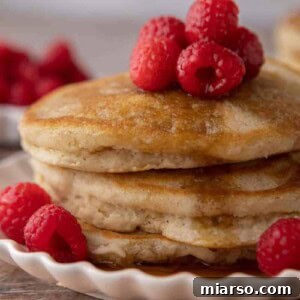 Stack of dairy-free pancakes topped with fresh raspberries