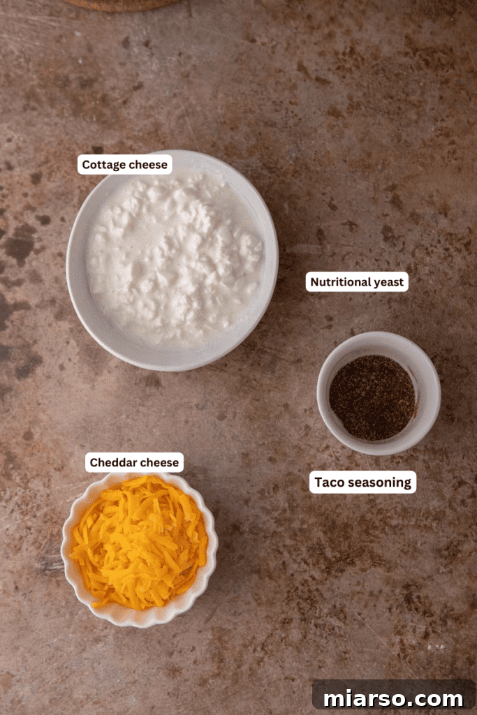 Assortment of fresh ingredients for cottage cheese queso on a wooden counter