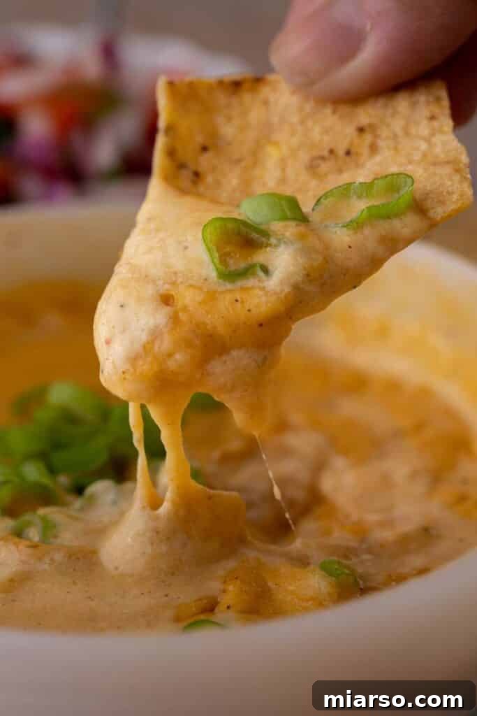 A hand dipping a tortilla chip into high-protein cottage cheese queso