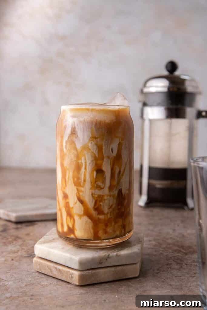 Quick 5-Minute Iced Caramel Coffee Perfection 9 A tall glass of homemade iced caramel coffee on a light background, highlighting its inviting appearance.