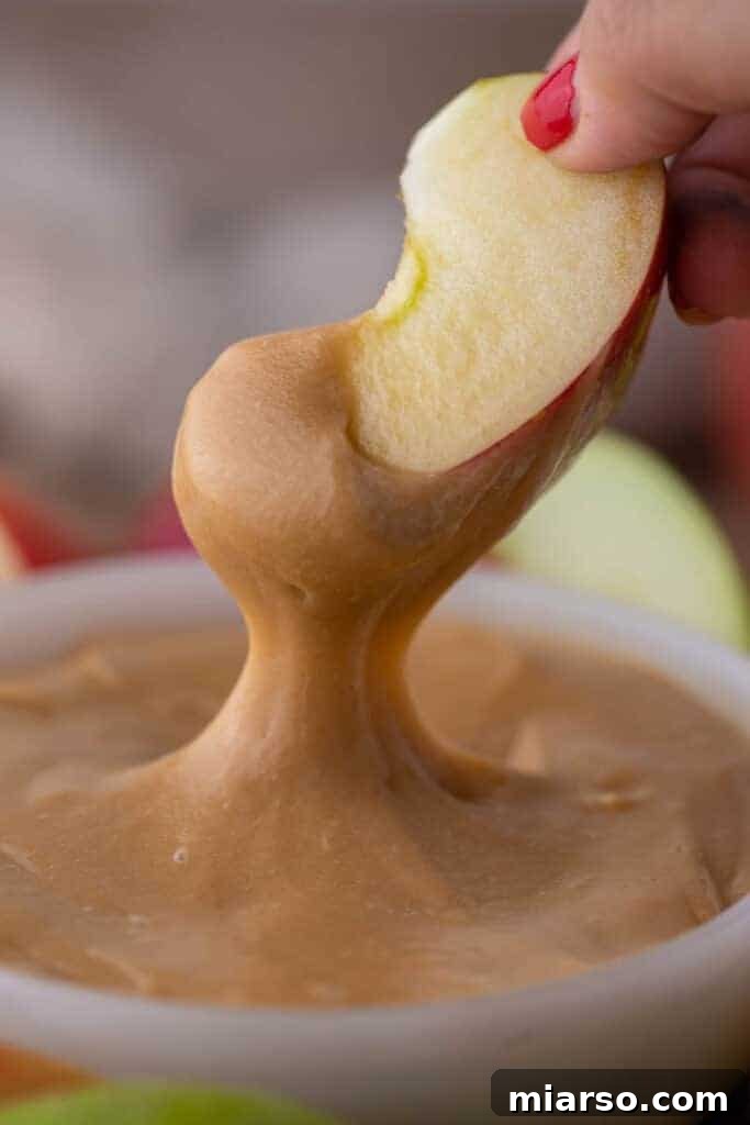 Crafting the Perfect Homemade Caramel Apple Dip 2 Crisp apple slice perfectly dipped in rich, golden homemade caramel sauce, ready to be enjoyed.