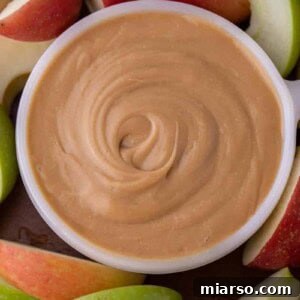 Overhead shot of caramel dip for apples in a bowl with sliced apples around it.