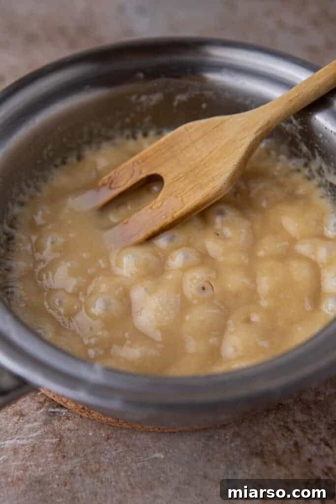 Crafting the Perfect Homemade Caramel Apple Dip 6 Caramel mixture gently boiling in a saucepan, illustrating the cooking process.
