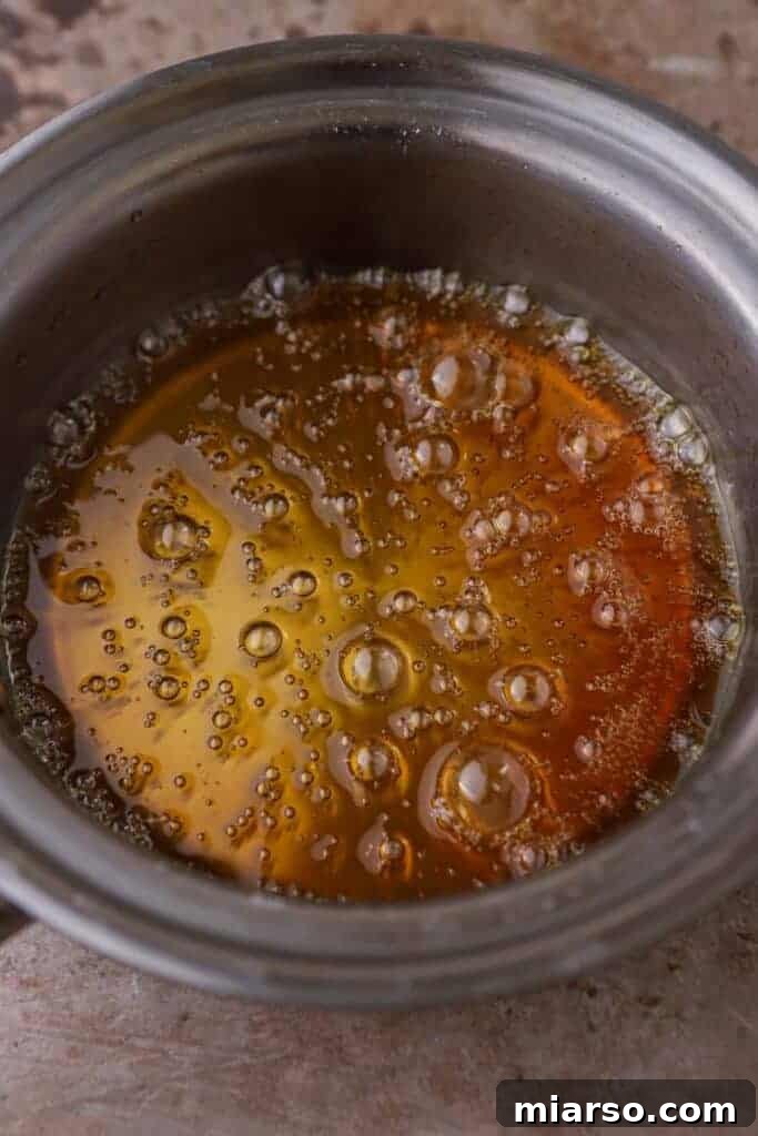 Close-up of bubbling caramel syrup in a pan, showing the early stages of caramelization.