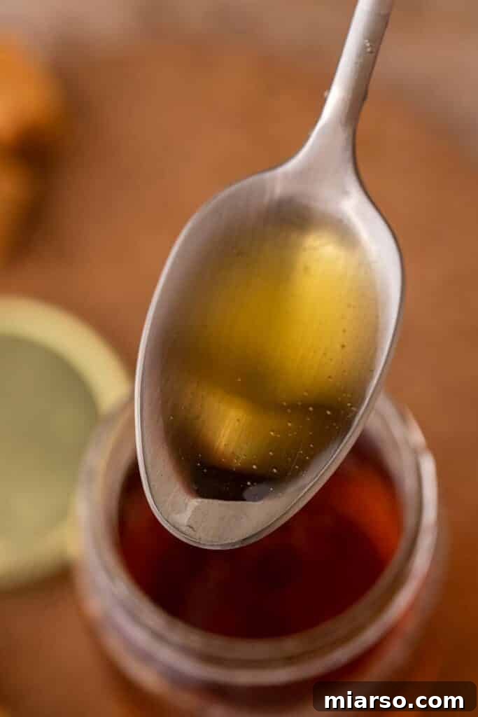 A spoonful of glistening caramel syrup for coffee, showcasing its golden color and smooth texture.