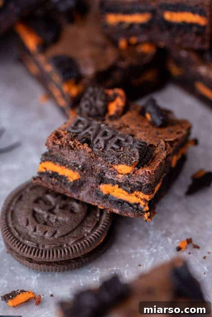 A close-up of a perfectly sliced Halloween Oreo brownie, revealing the layer of Oreos baked within the fudgy chocolate.