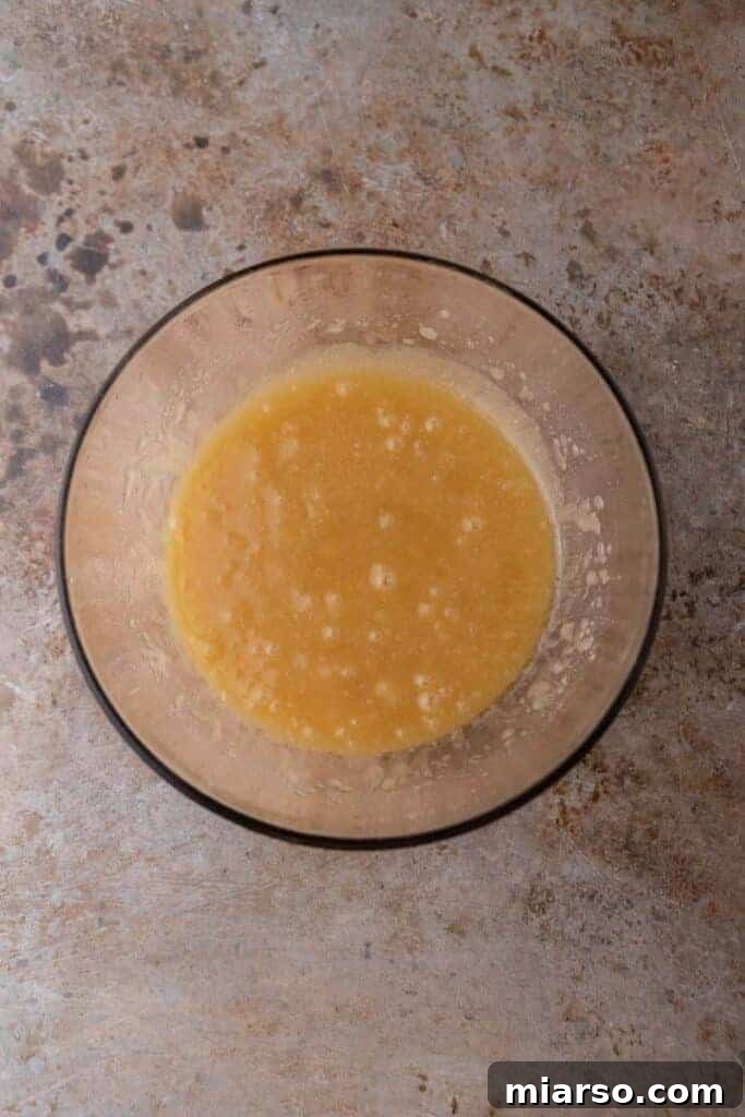Wet ingredients (melted butter, oil, and sugars) mixed together in a large glass bowl.