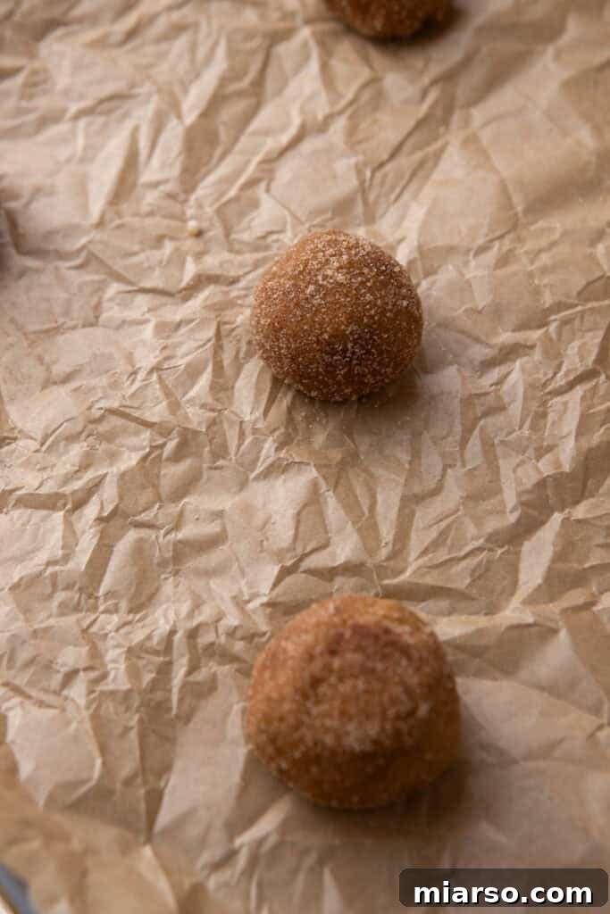 Cookie dough balls rolled in cinnamon sugar on a baking sheet