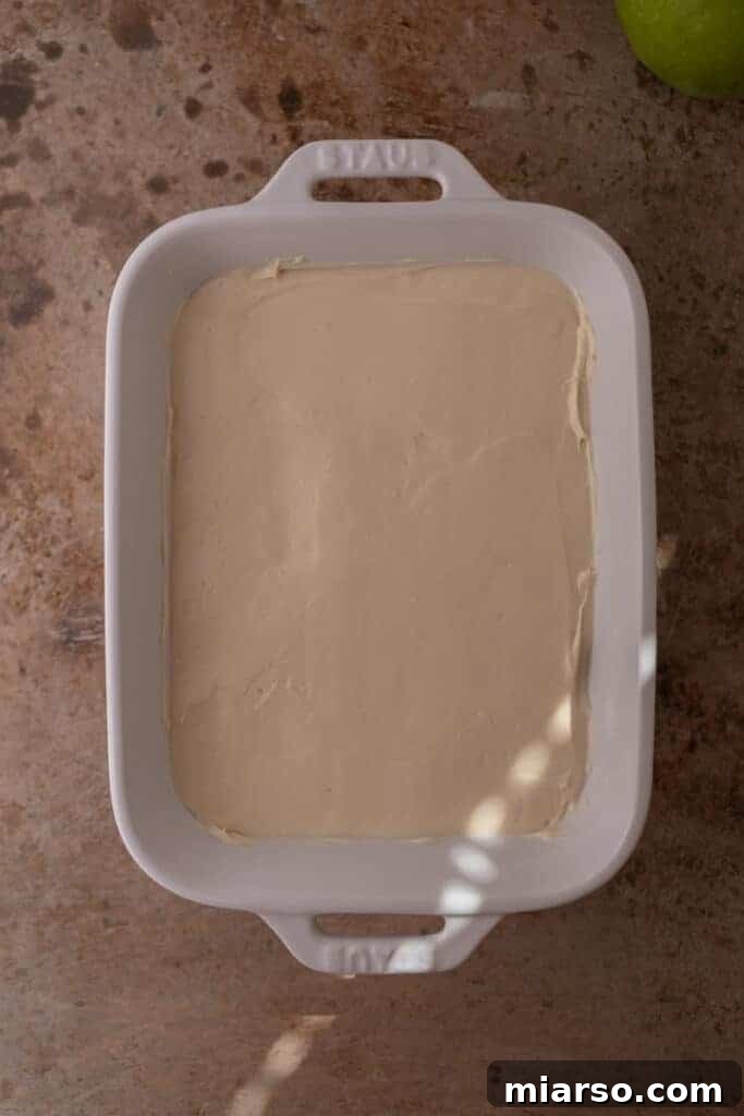 The smooth cheesecake layer spread evenly in a serving dish, ready for caramel.