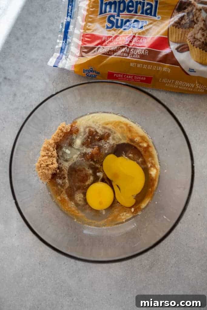 Wet ingredients for butter tart filling, including melted butter, brown sugar, and maple syrup, combined in a mixing bowl