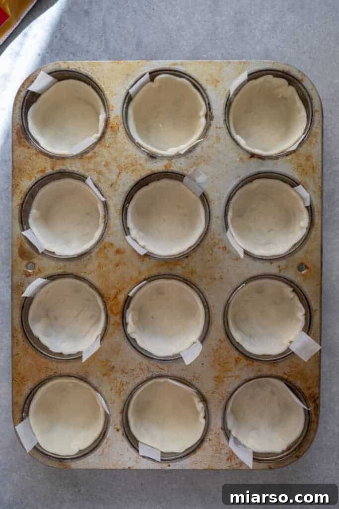 Pie crust pressed into individual muffin tin cups, forming neat tart shells